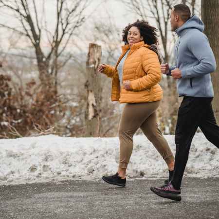 cheerful black couple jogging in snowy park